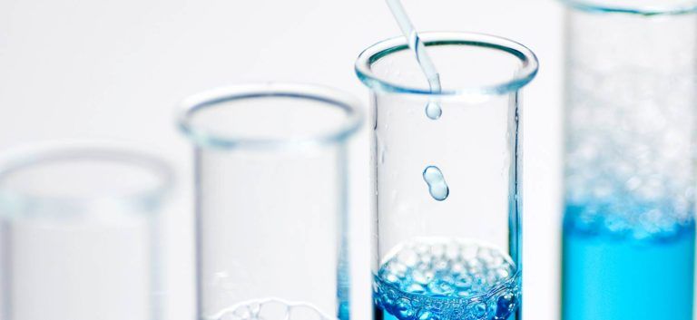 Blaue Flüssigkeit tropft in ein Reagenzglas