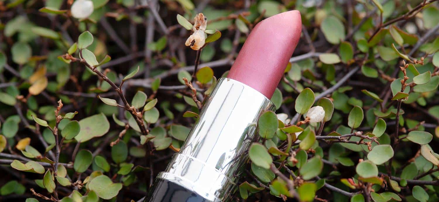 Rosa Lippenstift zwischen grünen Pflanzenn Zweigen