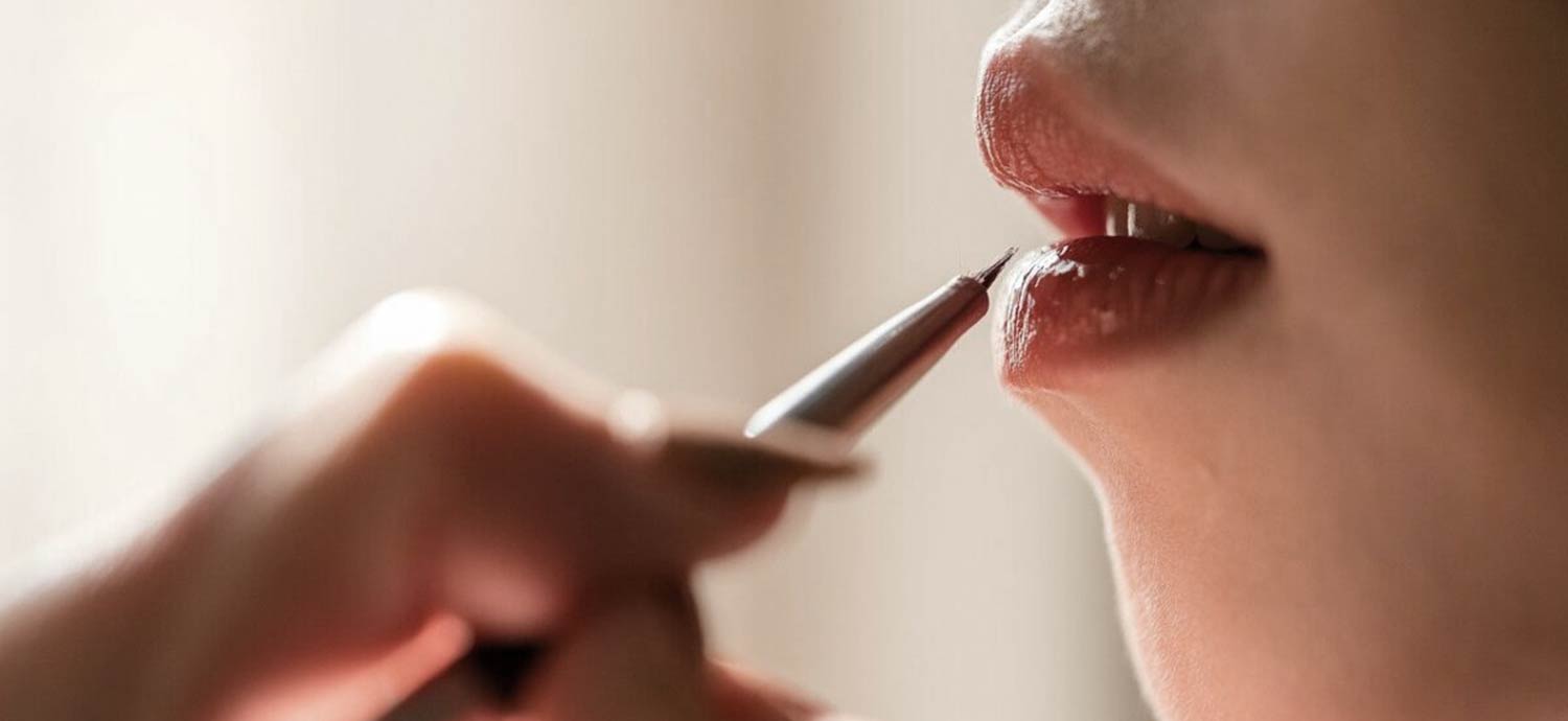 Frau trägt Lippenfarbe mit einem feinen Pinsel auf